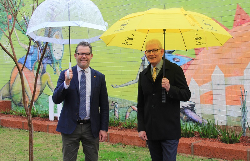City of Bayswater Mayor Dan Bull and RAC Group Executive Social and Community Impact Patrick Walker standing in front of a brightly painted wall holding umbrellas