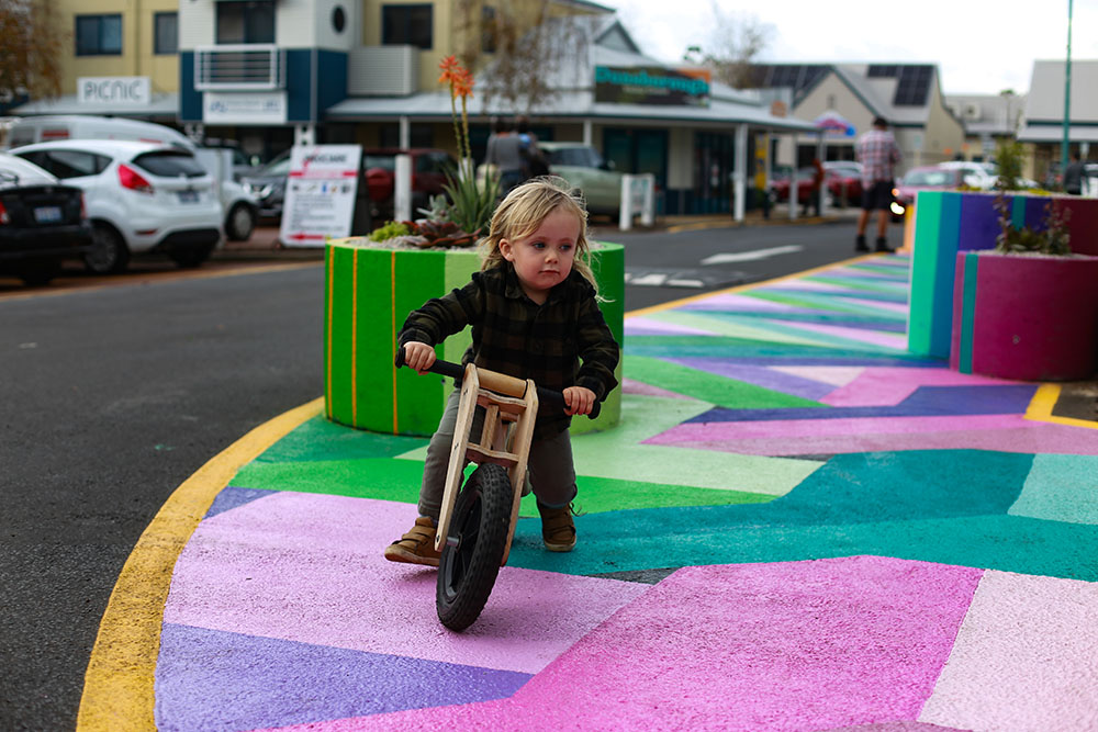 A young boy is riding his bike along a brightly painted footpath in Hannay Lane