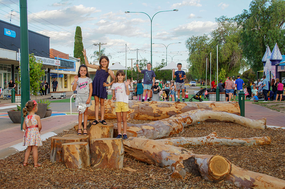 A group of children play on the log seating area in Merredin