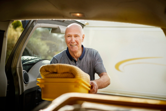 Elderly man packing boot of car