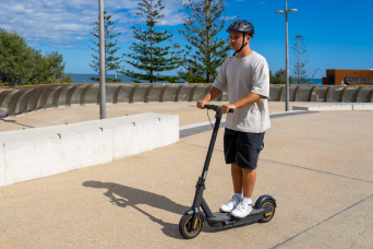 Young male riding e-scooter on footpath