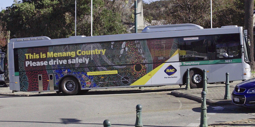 A bus covered in the artwork 'How the Menang Men Hunted the Gray Kangaroo' by Menang artist Michael Cummings. Over the artwork is text that reads "This is Menang Country. Please drive safely".
