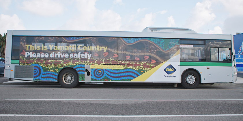 A bus covered in the artwork 'My Land' by Yamatji Noongar artist Godfrena Gilla. Over the artwork is text that reads "This is Yamatji Country. Please drive safely".