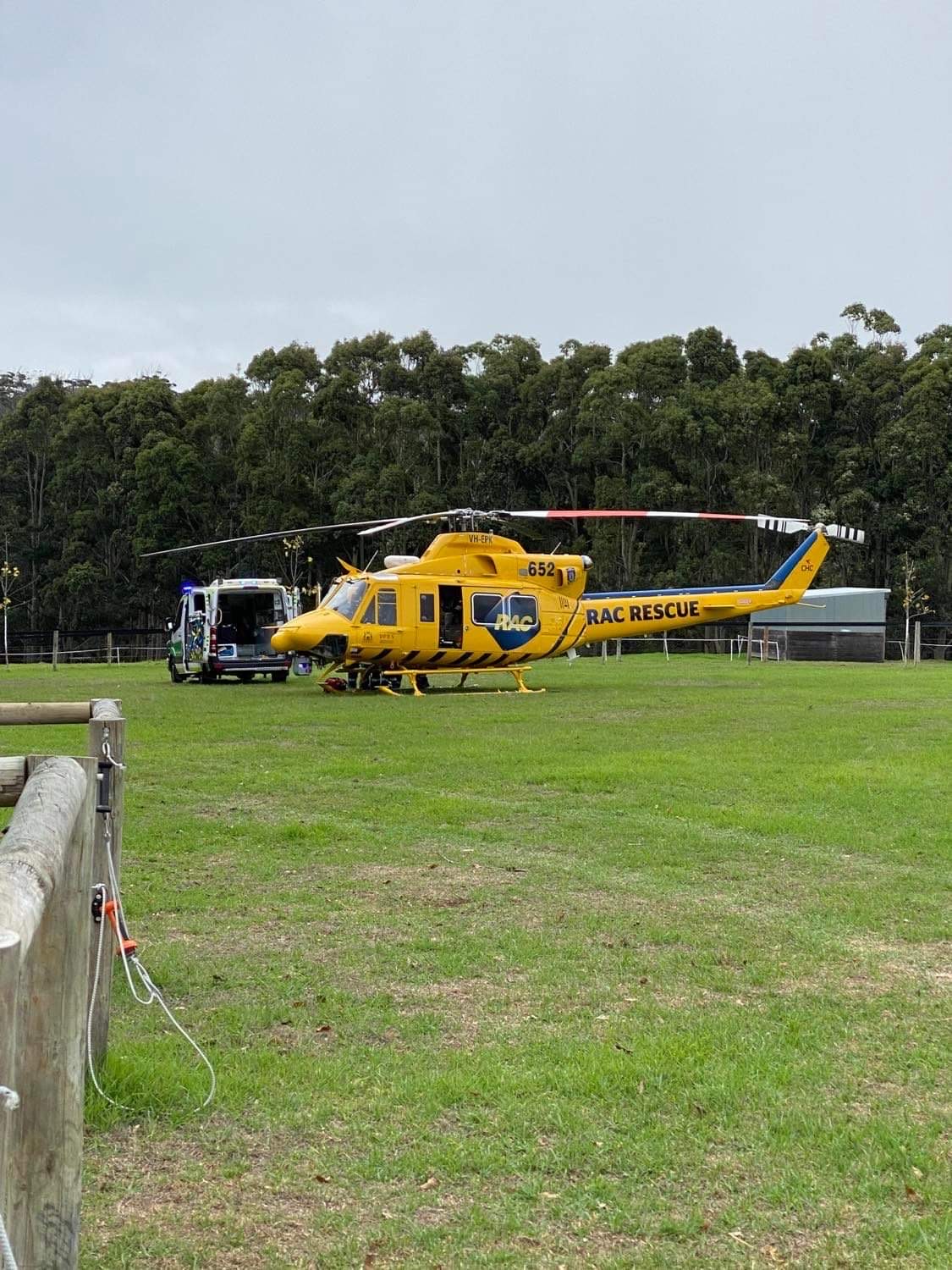 The RAC rescue helicopter is on the ground in a green paddock assisting a fallen horserider