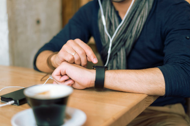 A man checking his smart watch at a coffee shop