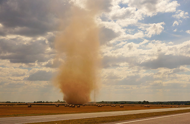 A dust devil forms over farmland