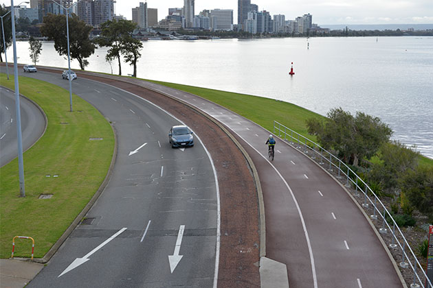 A cyclist on a bike path next to the Swan River