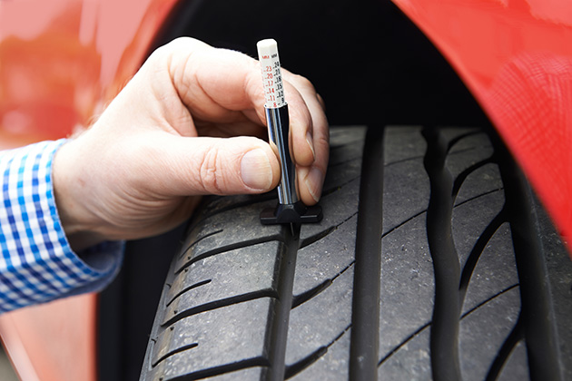 Person checking tyre tread with gauge