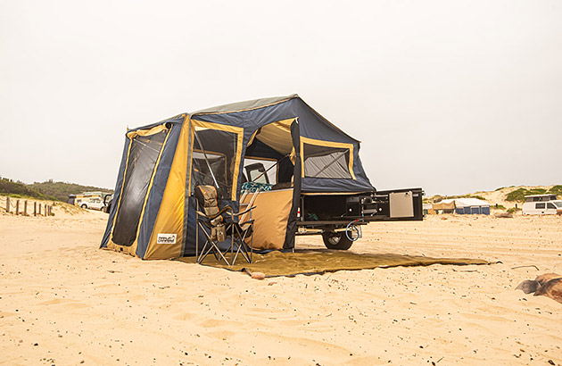 A camper trailer set up on a beach