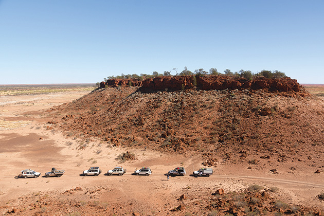 Cars driving next to large hill