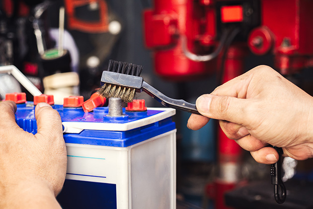 Person cleaning car battery terminal