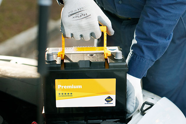 Gloved hands removing car battery