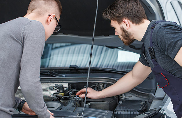 Two men checking a car's engine