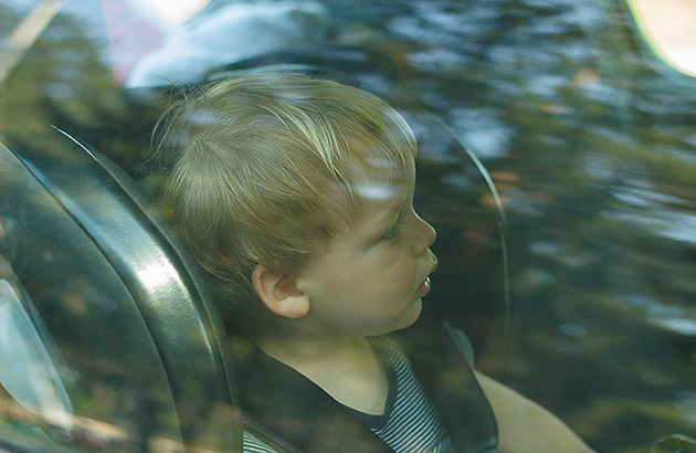 Child in a car seat seen through a car window