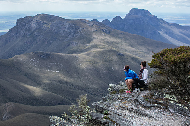 Two people sitting on top of a mountain