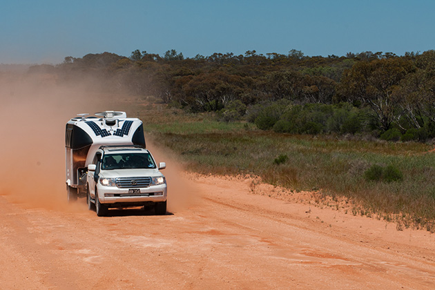 Caravan driving down dusty road