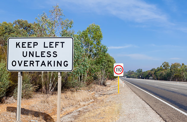 Keep left road sign on the side of a straight road