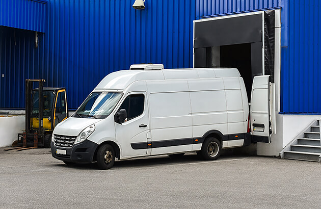A white van unloading goods at a warehouse