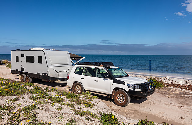 A caravan being towed by a 4WD on the beach