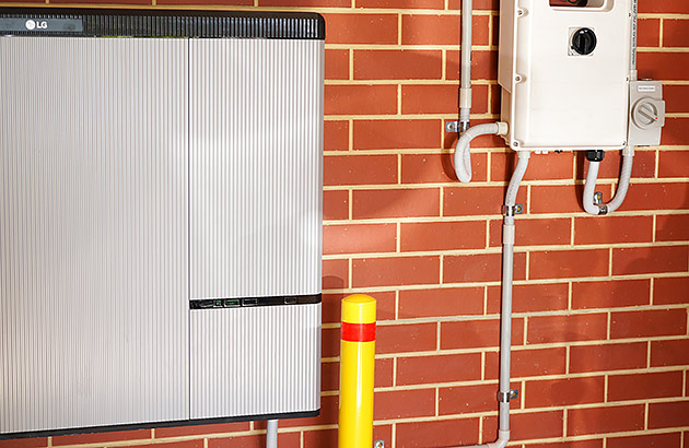 A home energy storage battery mounted on a red brick wall
