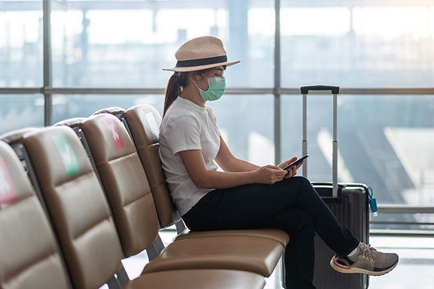 Woman with mask sitting at the airport