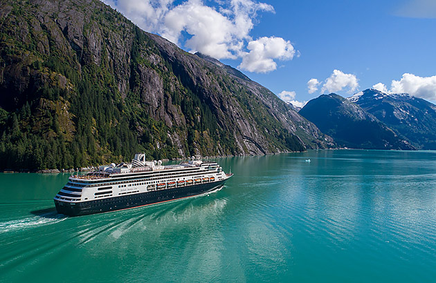 A cruise ship sailing past mountainous terrain