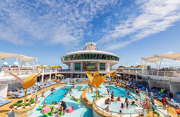 The deck on a Royal Caribbean ship showing passengers around pools