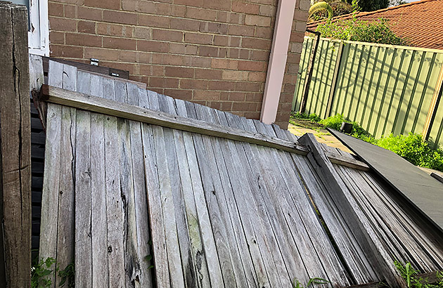 An old wooden picket fence which has been been blown over