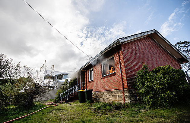  The exterior of a home with smoke coming from one of the windows