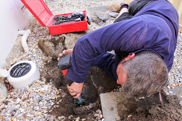 Plumber digging to expose copper pipe