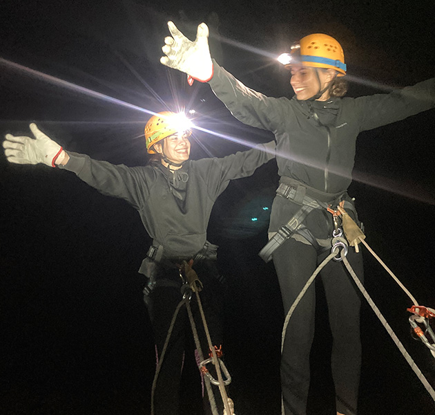 Two people abseiling in dark with torch