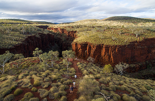 People walking on a path towards a red gorge in Karijini National Park
