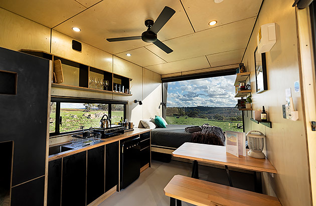 The interior of a tiny cabin showing the bed, kitchen and dining area