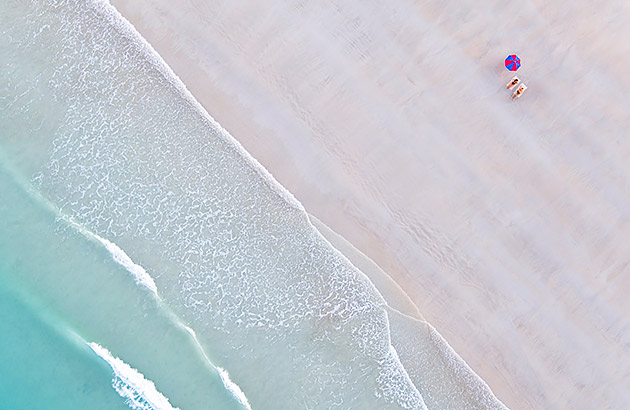 Two people relax under an umbrella on Cable Beach in Broome