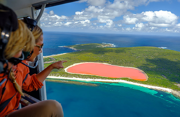 Two passengers in a helicopter flying over the pink lake Lake Hillier