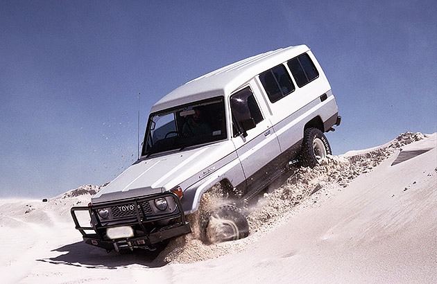 A white four-wheel drive coming down a sand dune