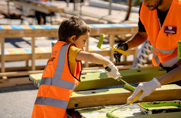 Young boy painting wooden pillar