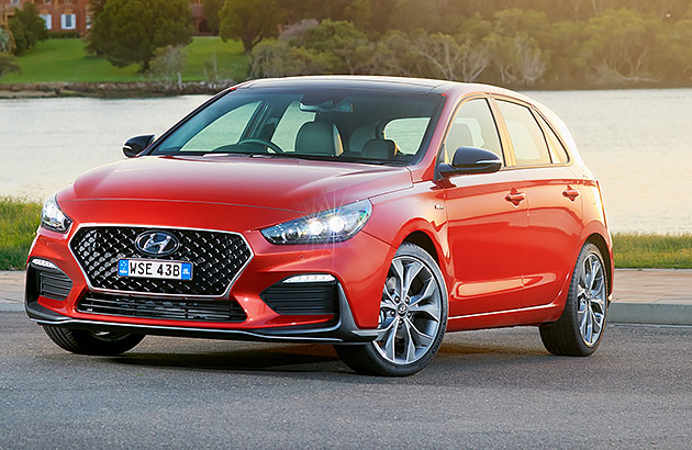 A red Hyundai i30 parked near a river