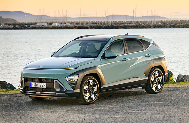 A green Hyundai Kona parked near a river