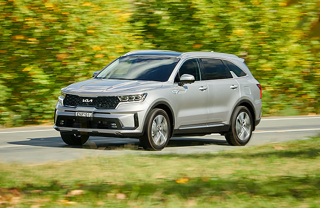 A grey Kia Sorrento Hybrid driving on a country road