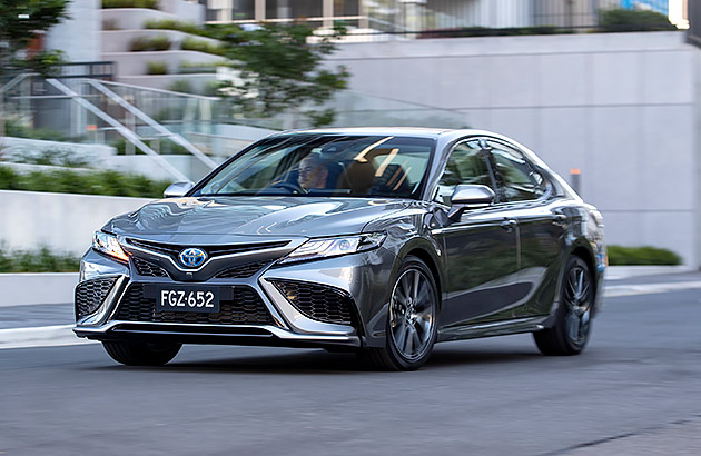 A grey Toyota Camry driving on a city street