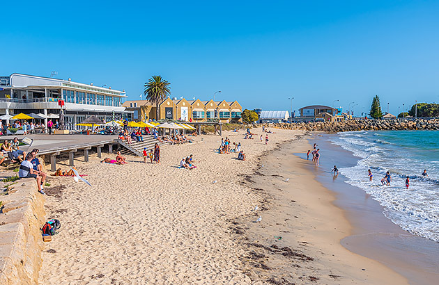 A side view along a beach from the water up to restaurants on the shore