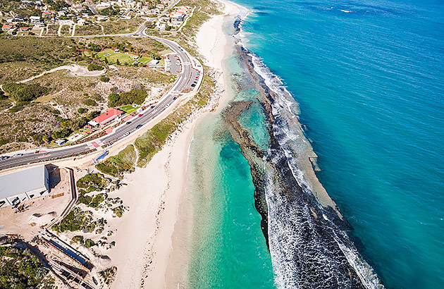 An aerial view of beach with a reef running parallel to the beachfront