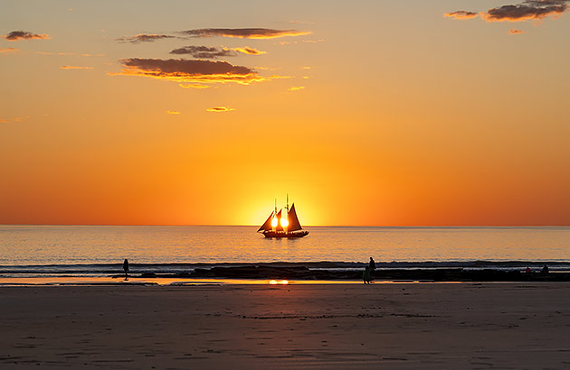 A pearl lugger sailing a long Cable Beach at sunset