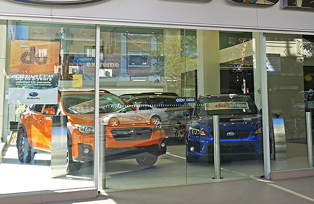 The window of a car dealership with cars visible inside