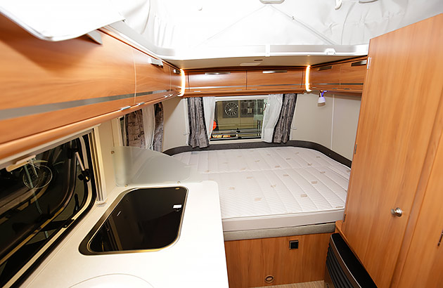 The interior of a caravan showing a bed and kitchen/dining area