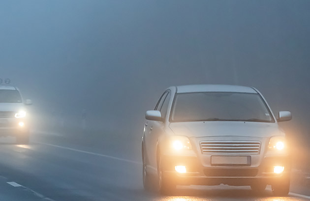 Two cars driving in fog at night