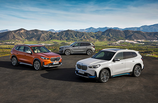 Three BMW SUVs on a tarmac with mountains in the background
