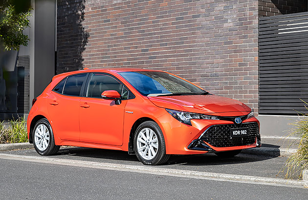 A red Toyota Corolla near a red brick wall