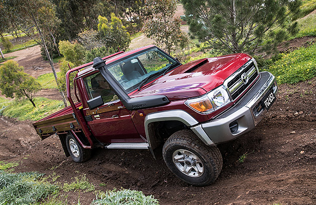 A red Toyota LandCruiser 70 Series on a dirt track